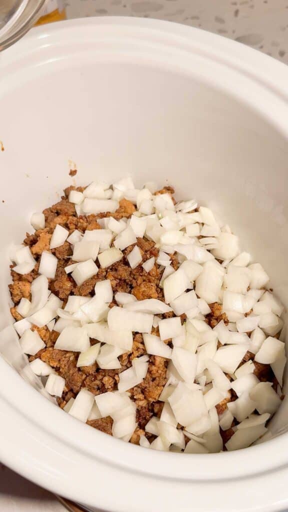 diced onions on top of cooked mixture in a slow cooker