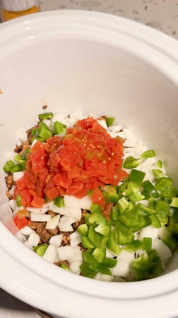 rotel, diced onions and green peppers on top of meat mixture in a crock pot