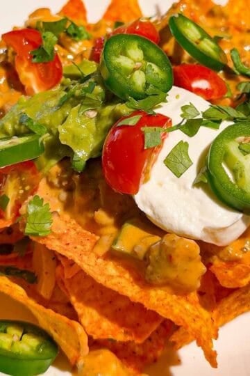 These Crock Pot Nachos are easy game day food, party appetizer or fun family dinner loaded with bold Tex-Mex flavor. This easy slow cooker nachos recipe combines seasoned ground beef, Italian sausage, onions, green peppers, Rotel, salsa con queso, cream cheese and shredded cheese for an extra creamy, meaty nacho topping. Spoon the cheesy Crock Pot nacho mixture over tortilla chips or Doritos, then add sour cream, guacamole, diced tomatoes, cilantro and jalapenos. If you need easy Crock Pot appetizers, slow cooker party food, football food ideas, Super Bowl snacks, nacho recipes or easy appetizers for a crowd, save this recipe. These loaded nachos are perfect for game day parties, potlucks, movie nights and casual entertaining when you want easy comfort food everyone will dig into!