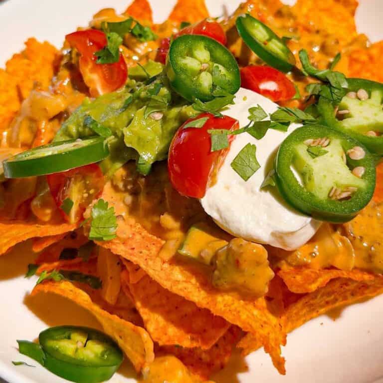 These Crock Pot Nachos are easy game day food, party appetizer or fun family dinner loaded with bold Tex-Mex flavor. This easy slow cooker nachos recipe combines seasoned ground beef, Italian sausage, onions, green peppers, Rotel, salsa con queso, cream cheese and shredded cheese for an extra creamy, meaty nacho topping. Spoon the cheesy Crock Pot nacho mixture over tortilla chips or Doritos, then add sour cream, guacamole, diced tomatoes, cilantro and jalapenos. If you need easy Crock Pot appetizers, slow cooker party food, football food ideas, Super Bowl snacks, nacho recipes or easy appetizers for a crowd, save this recipe. These loaded nachos are perfect for game day parties, potlucks, movie nights and casual entertaining when you want easy comfort food everyone will dig into!