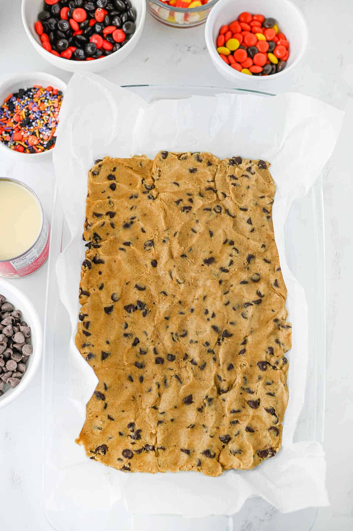 raw cookie dough pressed into a parchment lined baking dish