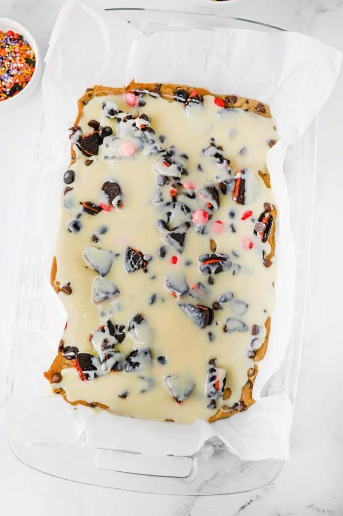 condensed milk poured over chocolate chip cookie dough in a baking dish