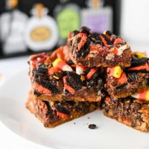 These Halloween Layer Bars are an easy Halloween dessert, loaded with chocolate chip cookie dough, Halloween Oreos, M&Ms, Reese’s Pieces, candy corn and festive sprinkles. If you’re looking for Halloween desserts for a party, Halloween treats for kids, easy Halloween baking ideas or fun Halloween party food, these gooey cookie bars check every box. A buttery chocolate chip cookie base is piled high with crushed Oreos, chocolate candy and sweetened condensed milk for rich, chewy layers in every bite. These Halloween cookie bars are perfect for a Halloween bake sale, classroom party, spooky movie night or October dessert table. Save this Halloween layer bars recipe when you need easy Halloween treats, candy corn desserts, Halloween Oreo desserts or a fun way to use Halloween candy!