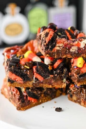 These Halloween Layer Bars are an easy Halloween dessert, loaded with chocolate chip cookie dough, Halloween Oreos, M&Ms, Reese’s Pieces, candy corn and festive sprinkles. If you’re looking for Halloween desserts for a party, Halloween treats for kids, easy Halloween baking ideas or fun Halloween party food, these gooey cookie bars check every box. A buttery chocolate chip cookie base is piled high with crushed Oreos, chocolate candy and sweetened condensed milk for rich, chewy layers in every bite. These Halloween cookie bars are perfect for a Halloween bake sale, classroom party, spooky movie night or October dessert table. Save this Halloween layer bars recipe when you need easy Halloween treats, candy corn desserts, Halloween Oreo desserts or a fun way to use Halloween candy!