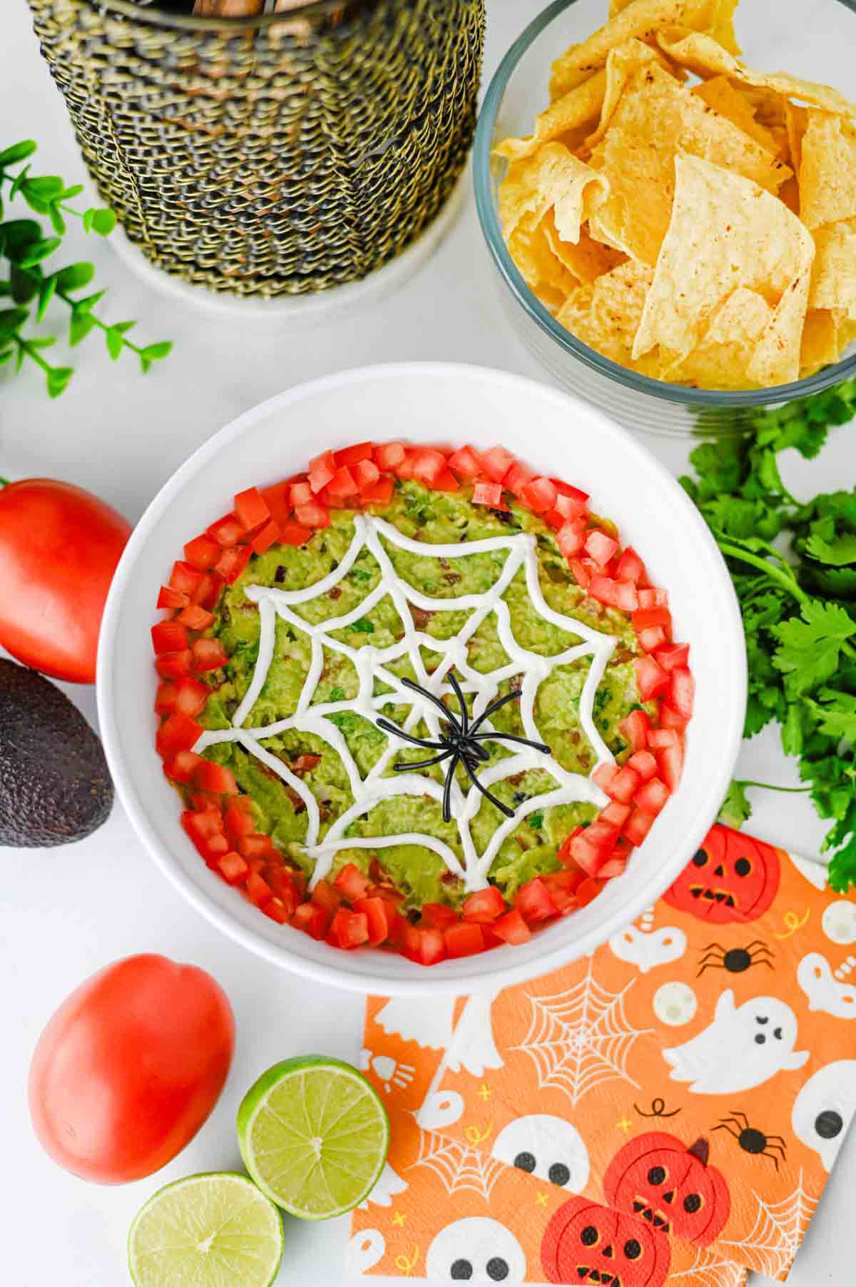 This Halloween Guacamole is the ultimate spooky appetizer for any spooky celebration! Creamy homemade guacamole with avocado, Roma tomatoes, red onion, fresh cilantro, and lime juice gets a festive makeover with an easy sour cream spider web on top. This Spider Web Guacamole is a fun Halloween dip that's ready in just 15 minutes and perfect with tortilla chips, crackers, or fresh veggies. If you need Easy Halloween Appetizers, Halloween Party Food, Halloween Dip Recipes, Spooky Halloween Food, Halloween Snacks for Kids, or Halloween Guacamole Ideas, this simple recipe belongs on your menu. Add diced tomatoes around the edge and a plastic spider for an extra creepy finish. It's an easy Halloween party appetizer that's fresh, colorful, delicious, and perfect for a Halloween snack table!