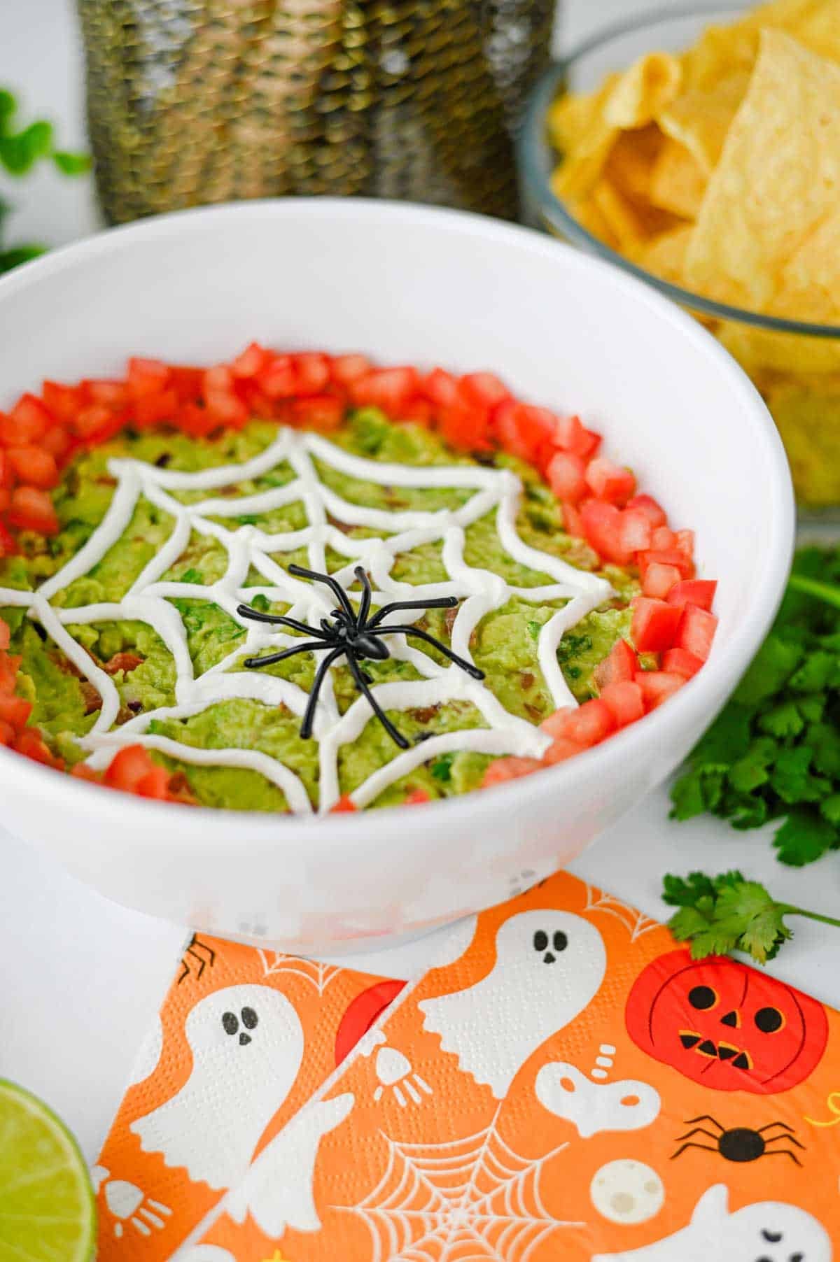 This Halloween Guacamole is the ultimate spooky appetizer for any spooky celebration! Creamy homemade guacamole with avocado, Roma tomatoes, red onion, fresh cilantro, and lime juice gets a festive makeover with an easy sour cream spider web on top. This Spider Web Guacamole is a fun Halloween dip that's ready in just 15 minutes and perfect with tortilla chips, crackers, or fresh veggies. If you need Easy Halloween Appetizers, Halloween Party Food, Halloween Dip Recipes, Spooky Halloween Food, Halloween Snacks for Kids, or Halloween Guacamole Ideas, this simple recipe belongs on your menu. Add diced tomatoes around the edge and a plastic spider for an extra creepy finish. It's an easy Halloween party appetizer that's fresh, colorful, delicious, and perfect for a Halloween snack table!