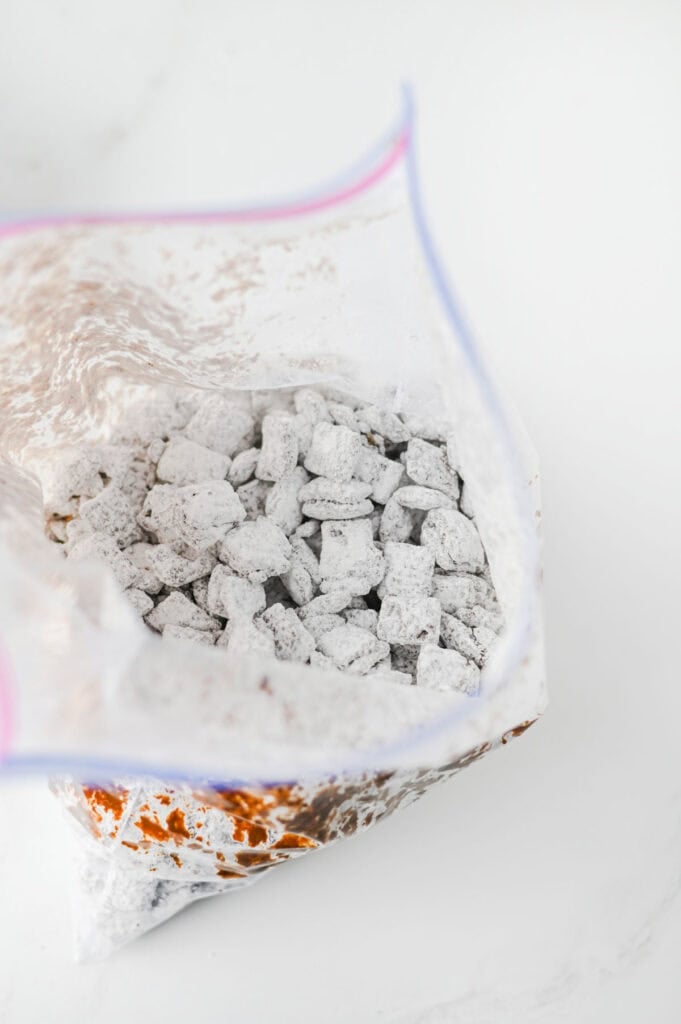chocolate coated chex cereal tossed in powdered sugar in a ziploc bag