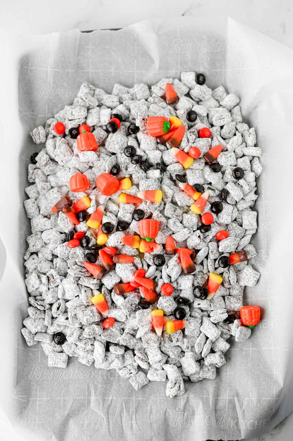 halloween muddy buddies on a parchment lined baking sheet