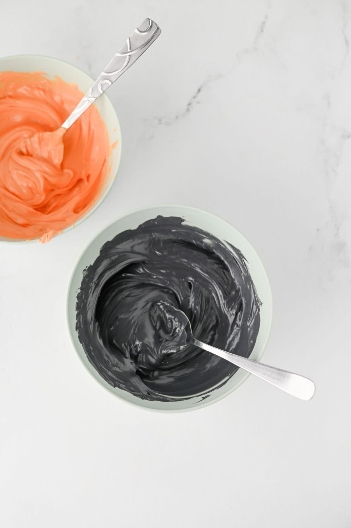melted black chocolate wafers and orange chocolate wafers in separate bowls