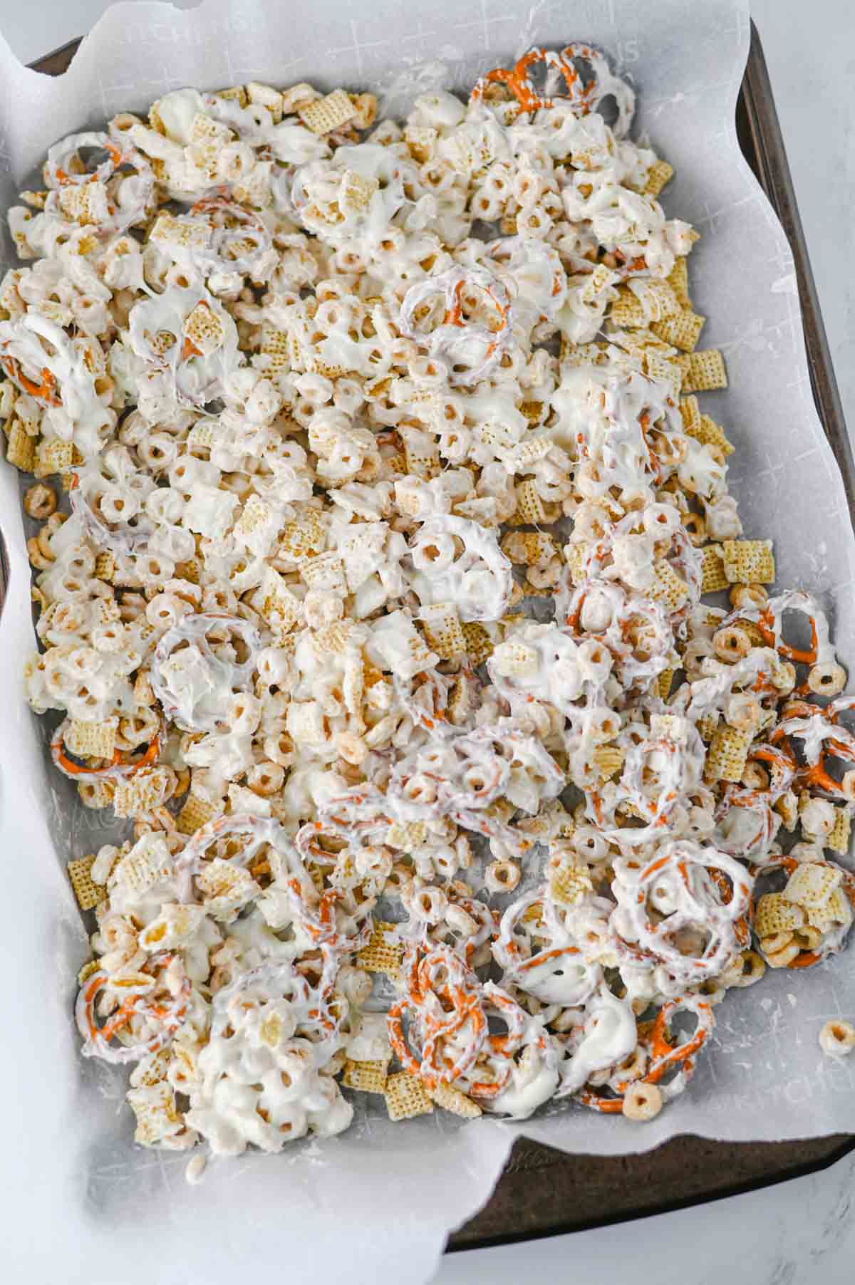 cereal and pretzels coated in white chocolate on a parchment lined baking sheet