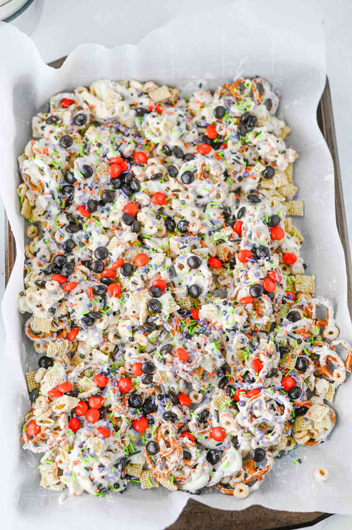 This easy Halloween Snack Mix is the ultimate sweet and salty treat for the spooky season! Made with Rice Chex cereal, Honey Nut Cheerios, pretzels, white chocolate, Halloween M&Ms, and colorful sprinkles, it's perfect for parties, movie nights, and trick-or-treating. If you need Halloween Snack Ideas, Halloween Party Food, Easy No Bake Halloween Treats, Fun Halloween Food, Halloween Treats For Kids, Halloween Chex Mix, or simple Halloween Desserts, this crunchy snack mix is a must-try. It takes just 15 minutes to prep, requires no baking, and is easy to make ahead. The sweet and salty combination makes every bite irresistible. Save this festive Halloween Party Snack Mix for a colorful, crowd-pleasing Halloween snack that kids and adults will keep grabbing by the handful!
