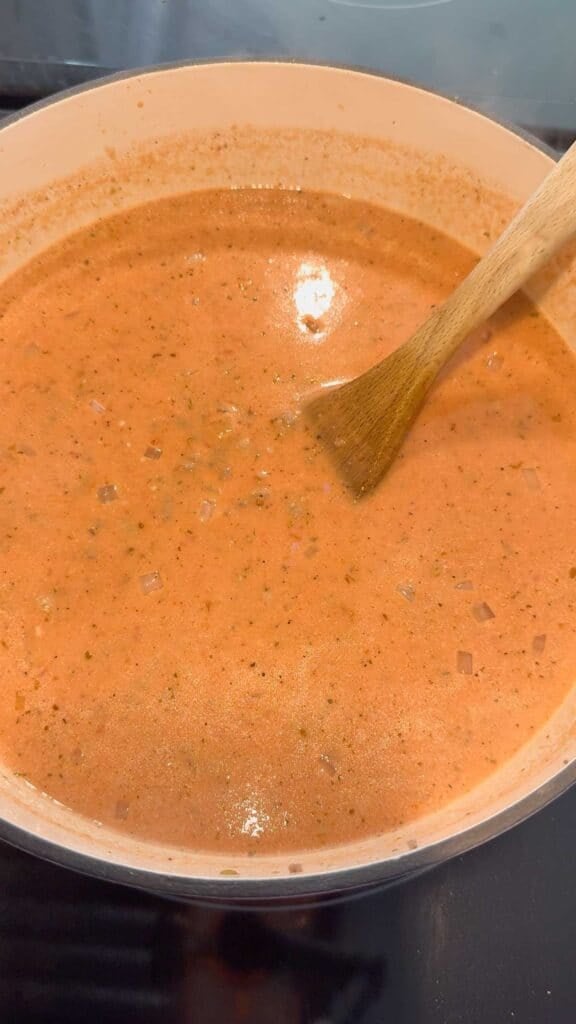 stirring heavy cream into tomato soup in a pot