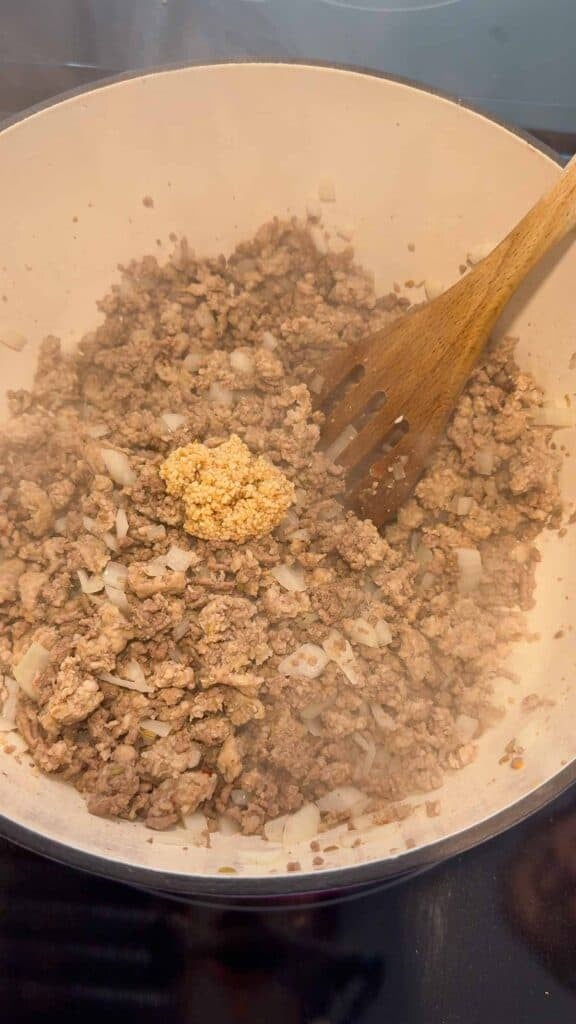 chopped garlic on top of cooked ground meat in a large pot