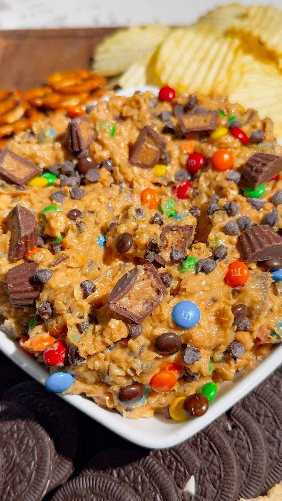 monster cookie dough dip with chips and cookies on a serving dish