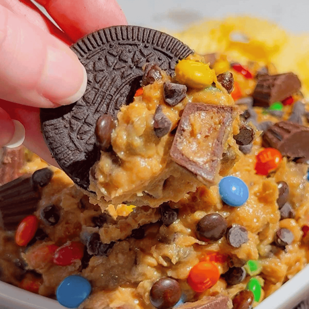This Monster Cookie Dough Dip is an easy no bake dessert dip loaded with crunchy peanut butter, brown sugar, quick oats, mini chocolate chips, mini M&Ms and chopped Reese’s peanut butter cups. It’s the perfect sweet party dip for holidays, birthdays, game day, potlucks, movie nights and easy entertaining. Serve this creamy peanut butter cookie dough dip with graham crackers, pretzels, vanilla wafers, cookies or apple slices for a fun dessert board everyone will dig into. If you love monster cookies, peanut butter desserts, cookie dough dip recipes, M&M desserts, Reese’s desserts and quick no bake treats, this 15 minute dessert dip is a must try for your next party or family gathering.