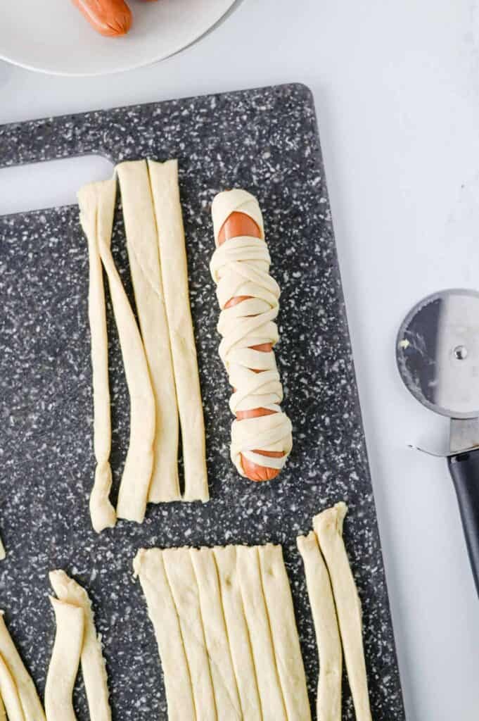 strips of crescent roll doll wrapped around a hot dog