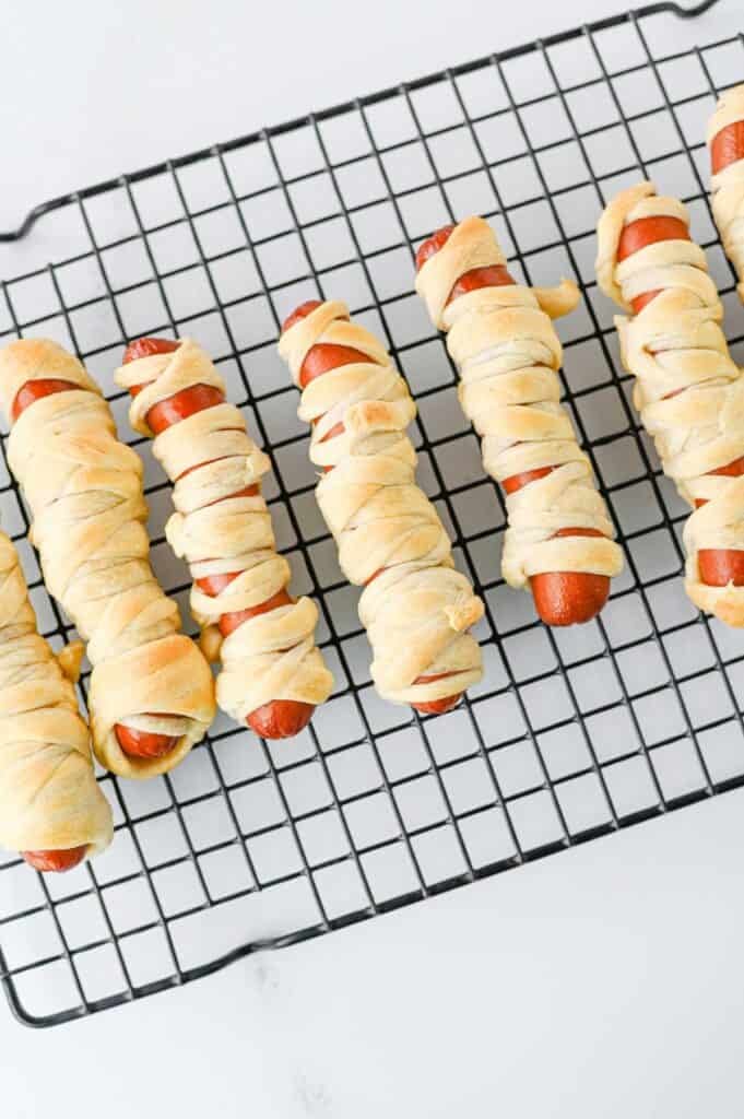 mummy hot dogs on a wire rack after baking