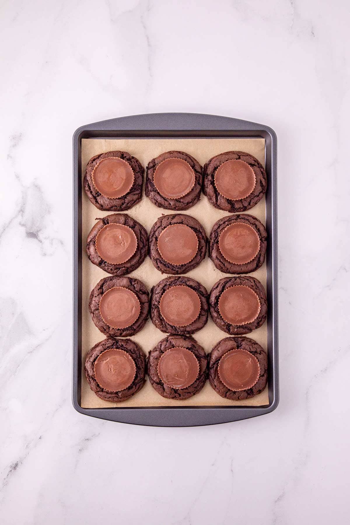 peanut butter cups on top of chocolate cookies on a baking sheet