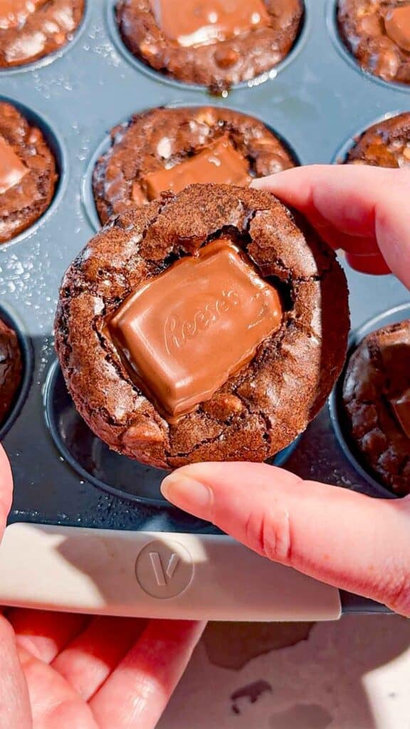 Reese's Stuffed Peanut Butter Brookies are the ultimate dessert for chocolate and peanut butter lovers! These easy muffin tin brookies start with Pillsbury peanut butter cookie dough, then get loaded with Reese's Peanut Butter Cups, Reese's brownie batter and pieces of Reese's peanut butter bar. Ready in just 33 minutes, this easy brookie recipe is perfect for parties, potlucks, holidays or whenever you need an indulgent treat. Save this recipe if you love Reese's desserts, peanut butter cup recipes, brownie cookie desserts, stuffed brookies, easy brownie mix recipes and muffin tin desserts. Every bite has a chewy peanut butter cookie base, a gooey candy center and a fudgy brownie top. These brownie cups are easy to serve and packed with chocolate peanut butter flavor!