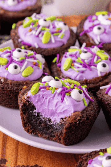 These Witch Cauldron Brownies are a fun and easy Halloween dessert recipe made with boxed fudge brownie mix, cream cheese frosting, purple gel food coloring and spooky Halloween sprinkles. Baked in muffin tins and pressed into little cauldron shapes, these cute Halloween brownies are perfect for Halloween baking ideas, Halloween party food, classroom treats, spooky desserts, Halloween brownie bites and kid friendly Halloween treats. The fudgy brownie cups are filled with colorful frosting and topped with candy eyes, bones or festive sprinkles for a creepy cute treat that looks impressive but starts with simple brownie mix. Add pretzel sticks or Pocky for little stirring spoons and serve these witch cauldron treats at your next Halloween dessert table or movie night.