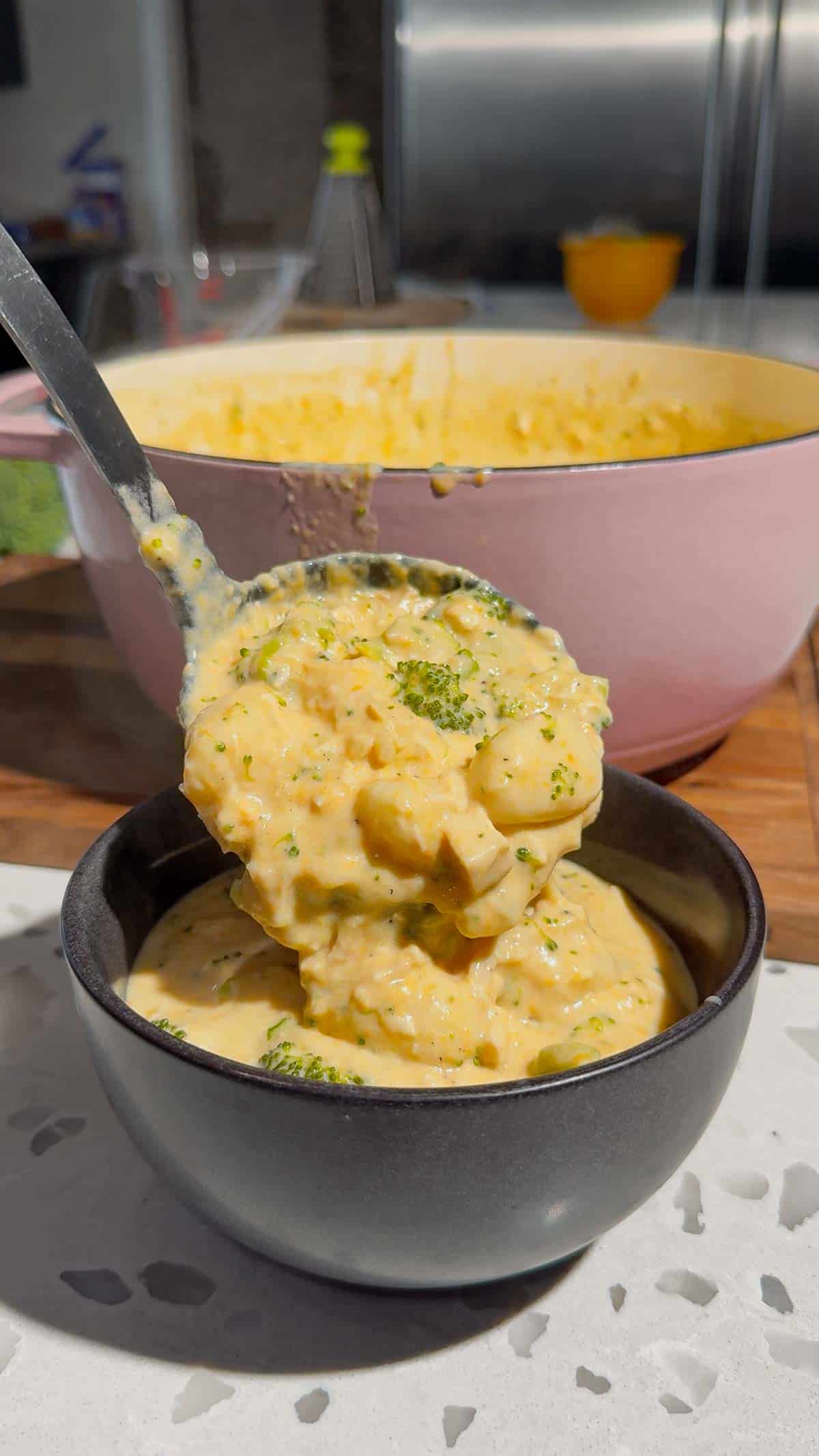 ladling broccoli cheddar chicken gnocchi soup into a bowl