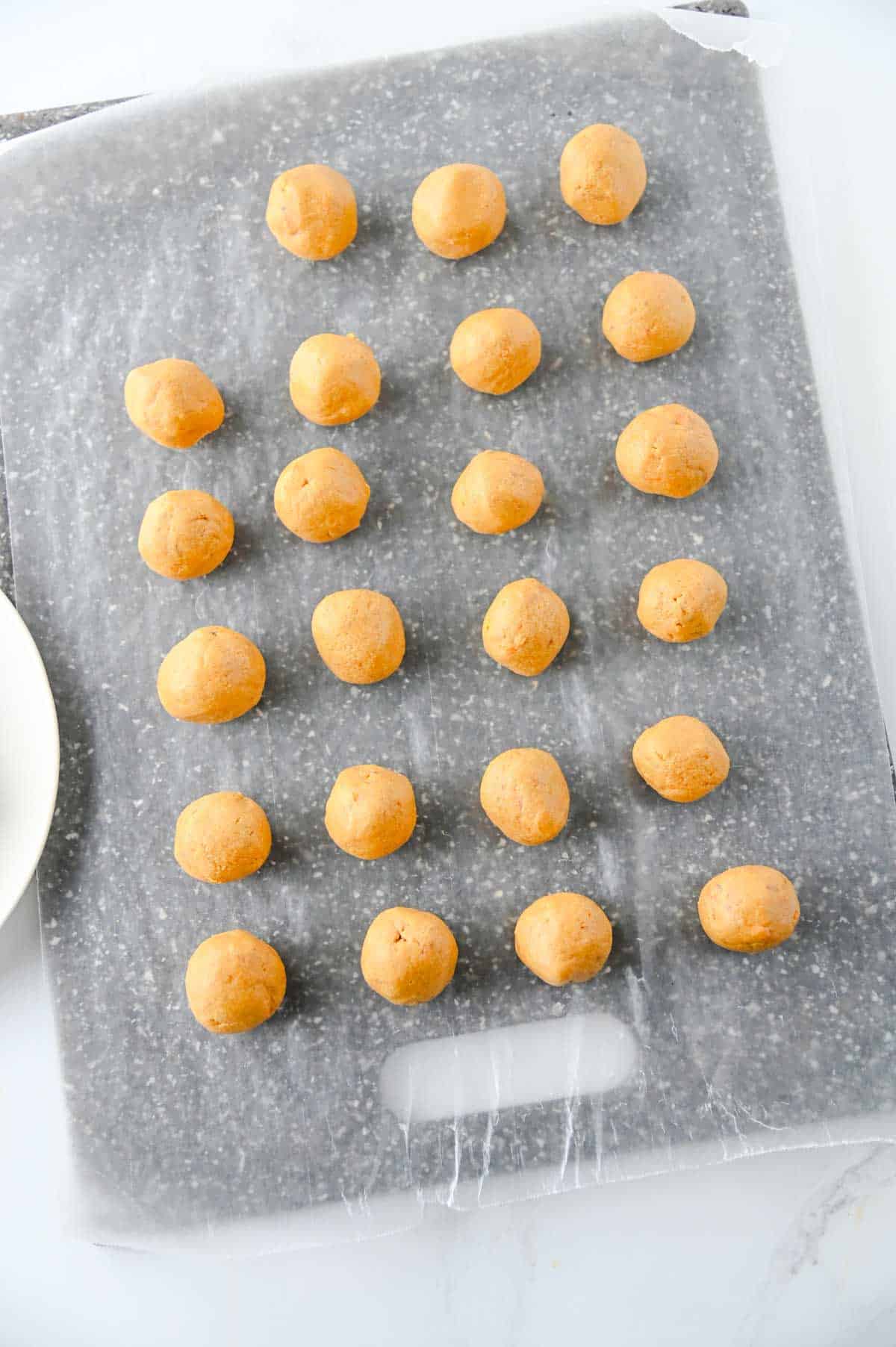 peanut butter butterfinger balls on a parchment lined baking sheet