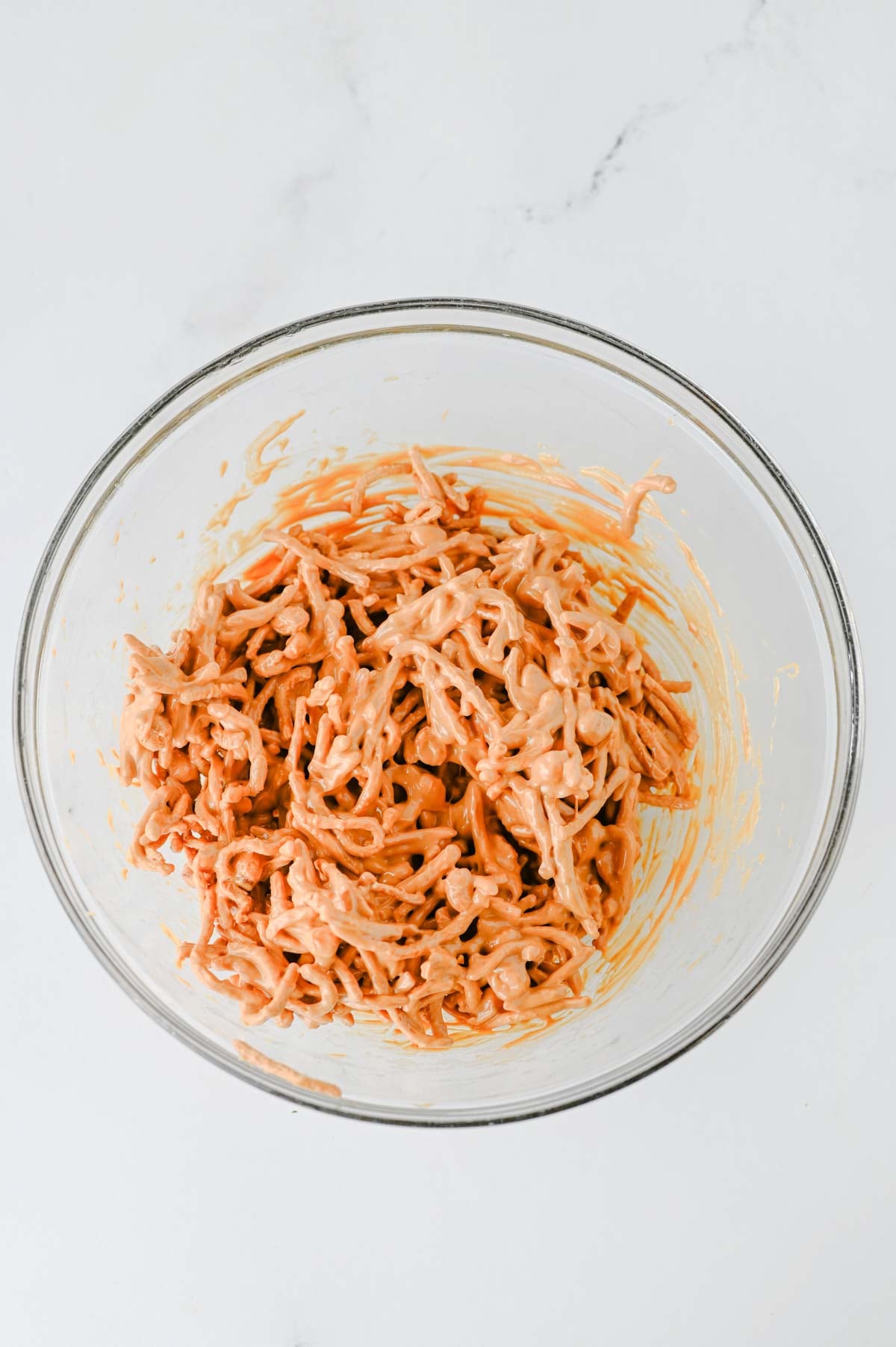 melted butterscotch chips and peanut butter coating chow mein noodles in a glass bowl