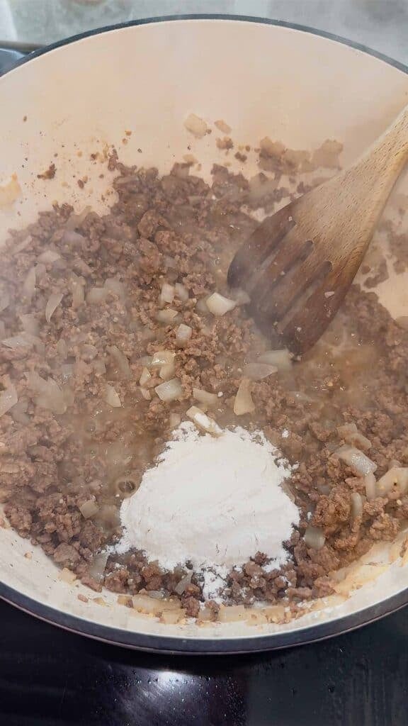 flour added to pot with cooked ground beef and diced onions
