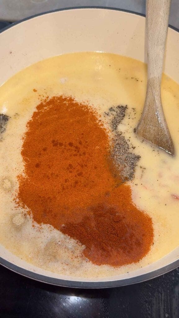seasonings added to creamy soup in a pot