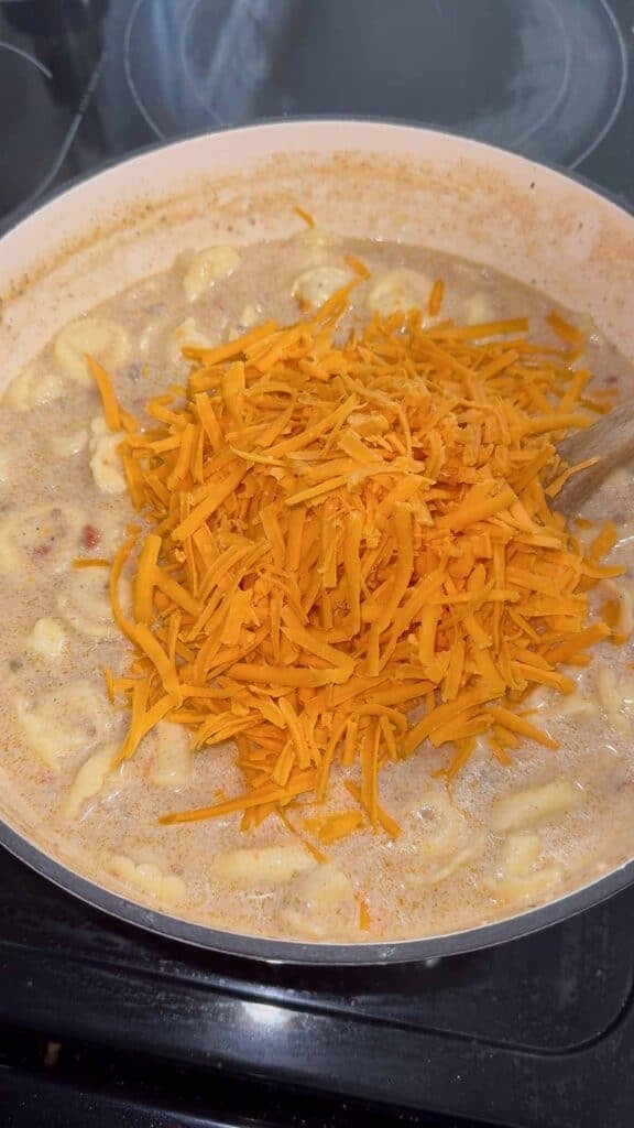 shredded cheddar added to pot of tortellini soup