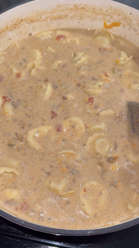 stirring cheeseburger tortellini soup in a pot