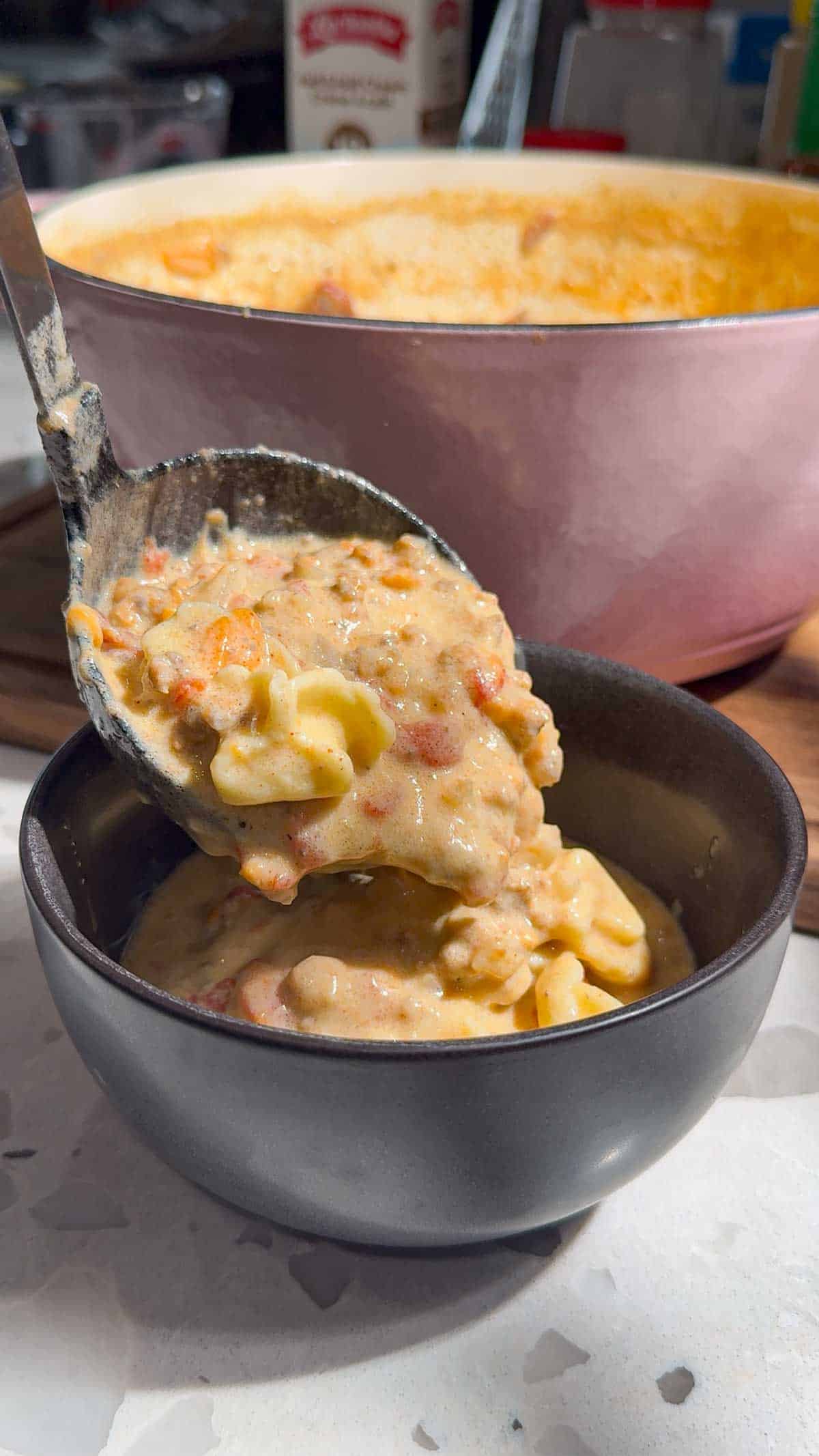 ladling cheeseburger tortellini soup into a bowl