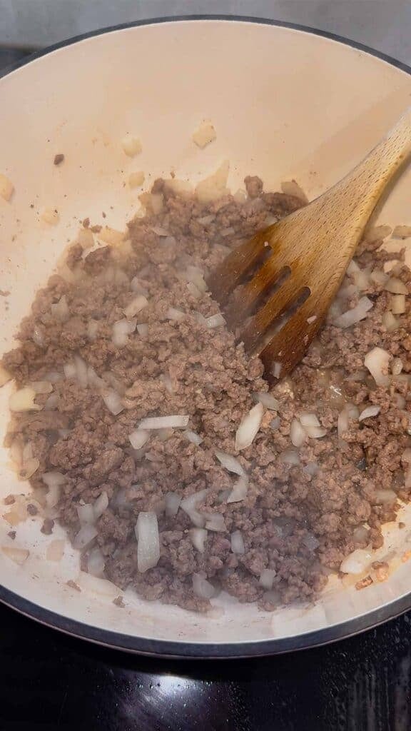 cooking ground beef and diced onions in a dutch oven
