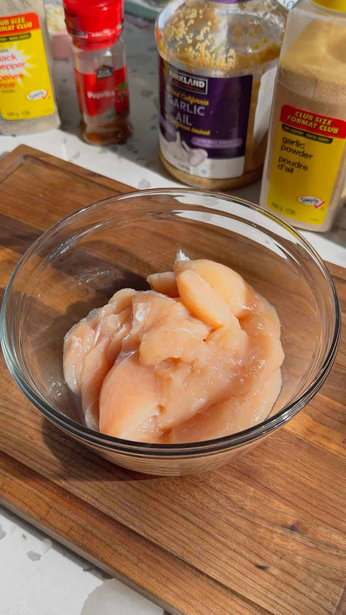 sliced raw chicken breasts in a glass bowl