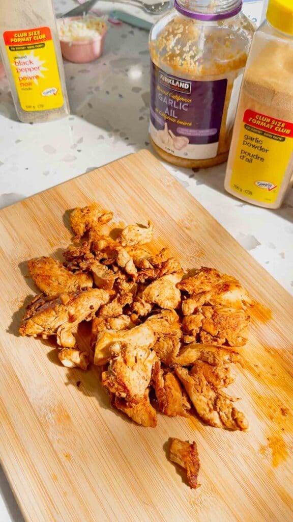 cooked, seasoned chicken breast pieces on a cutting board