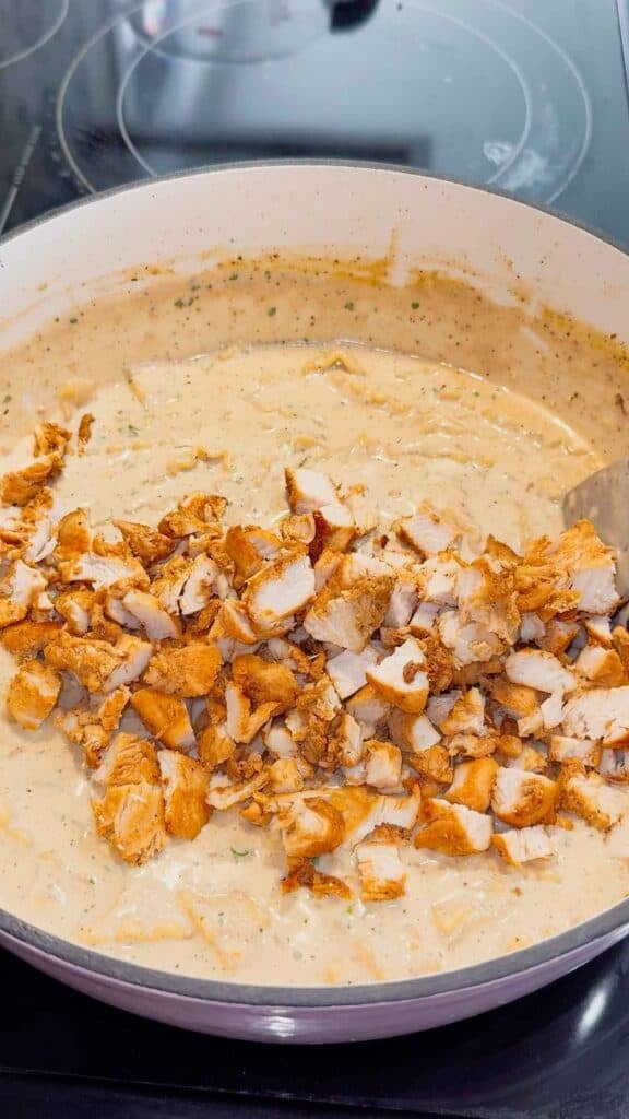chopped chicken breast pieces added to pot of creamy lasagna soup