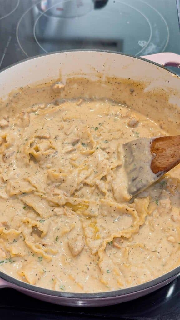 stirring creamy chicken alfredo soup in a pot