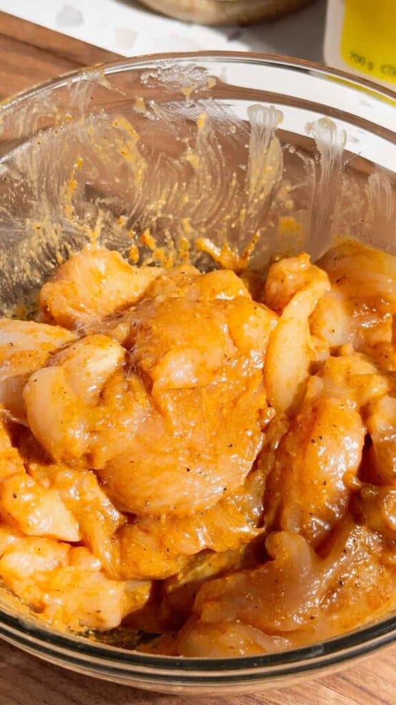 raw seasoned chicken breast slices in a glass bowl