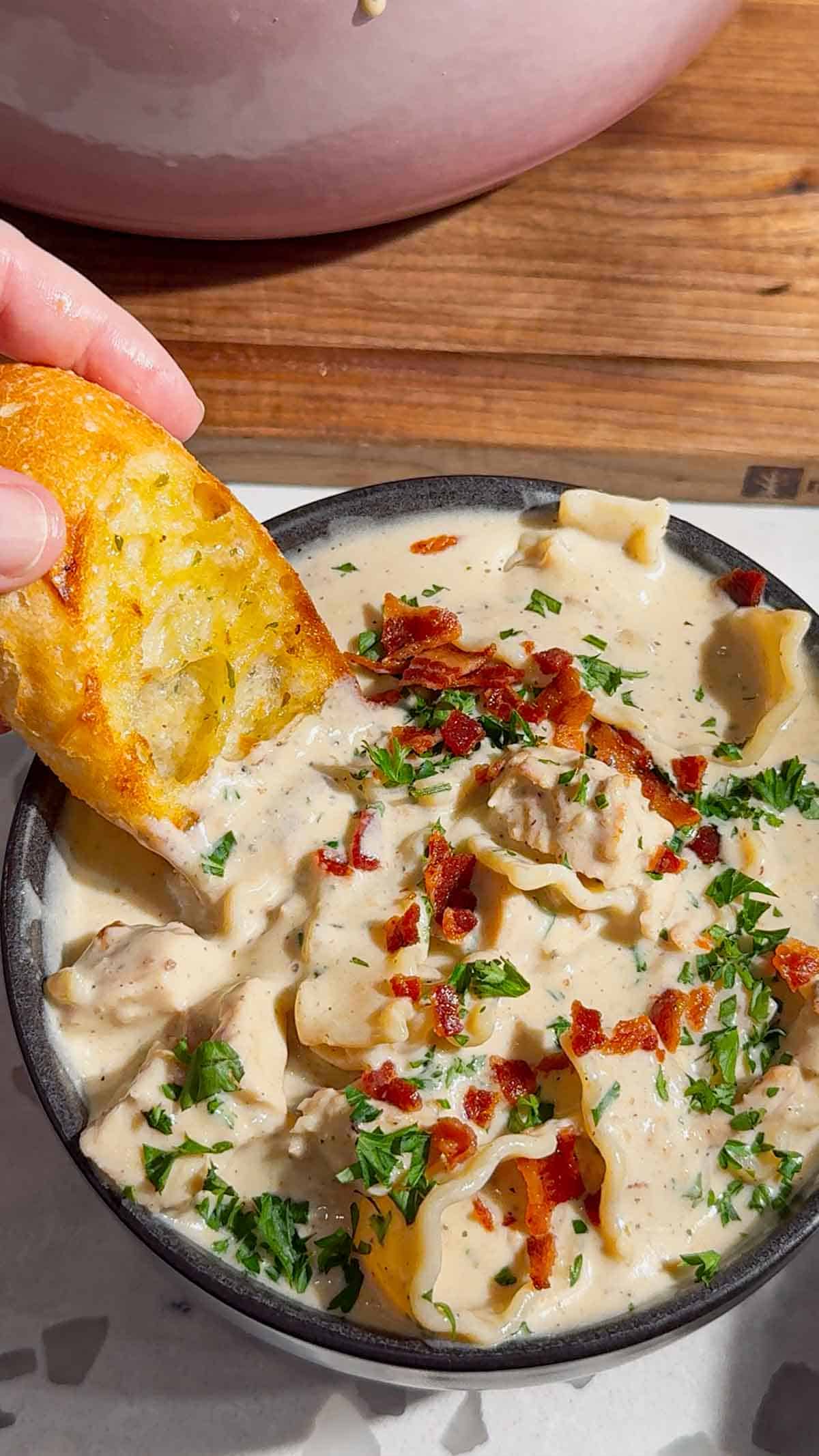 dipping baguette slice in chicken alfredeo lasagna soup