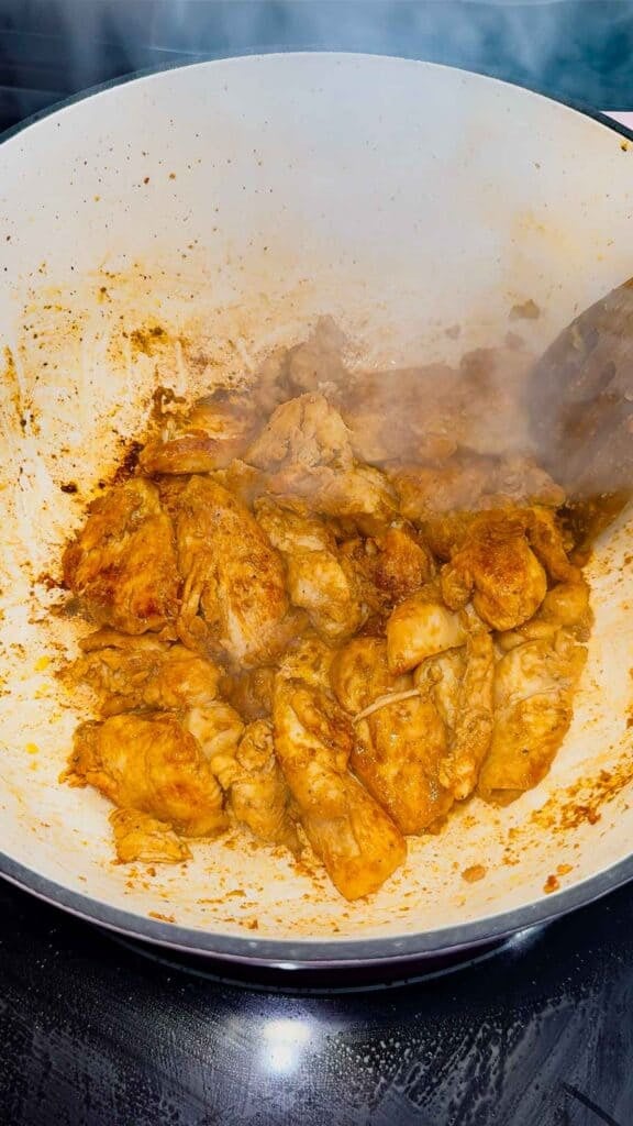 seasoned chicken breast pieces cooking in a dutch oven
