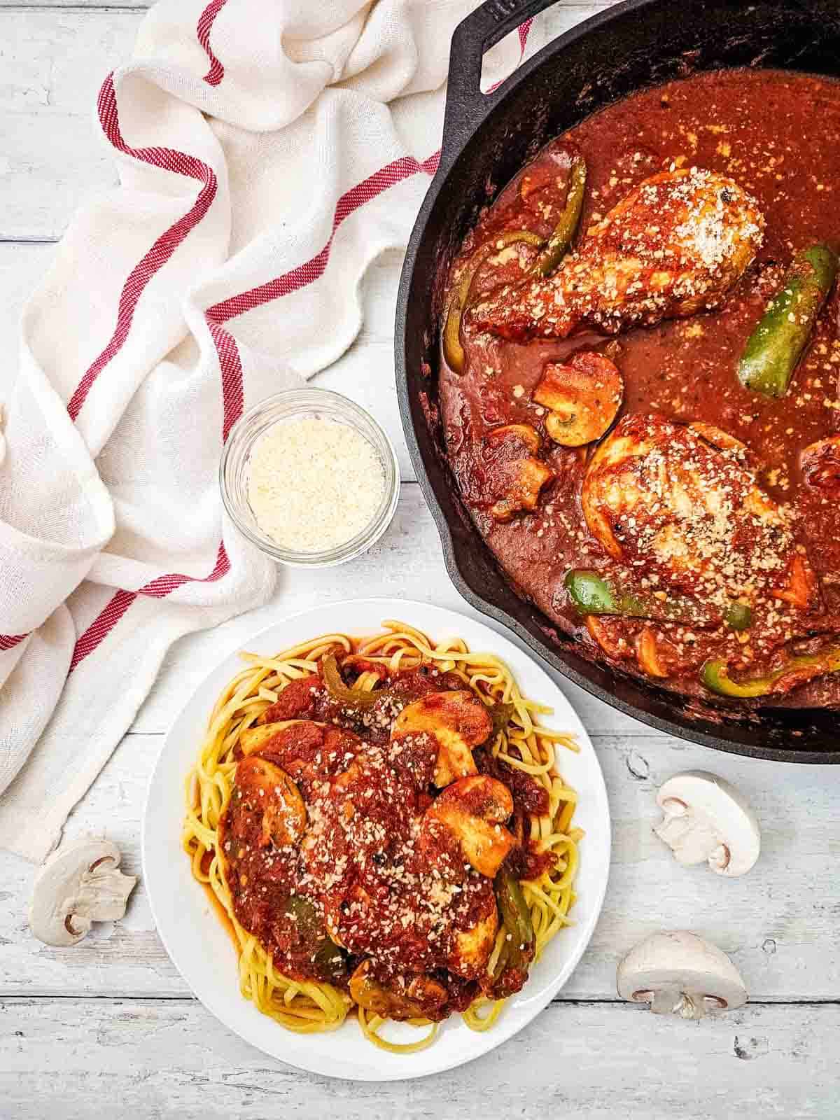 chicken cacciatore in a skillet and on a plate over noodles