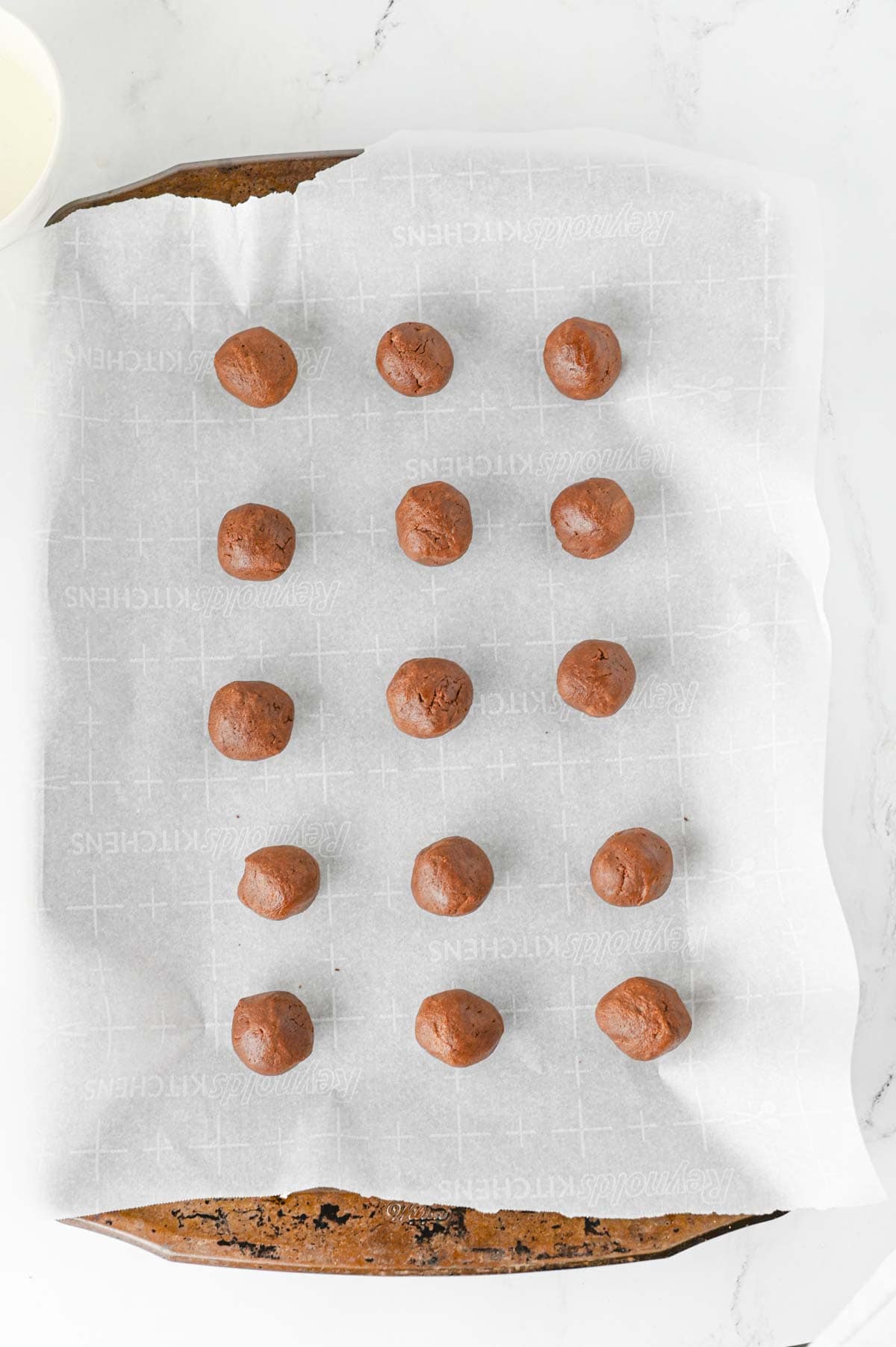 balls of chocolate cookie dough on a parchment lined baking sheet