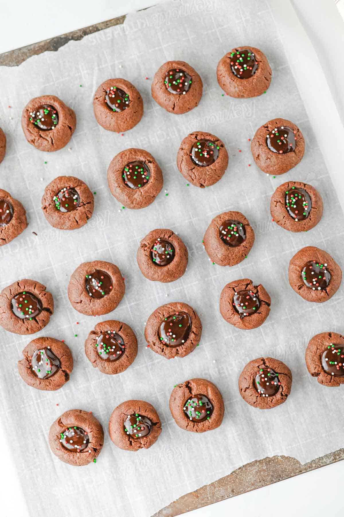 sprinkles on top of thumbrpint cookies laid out on parchment paper
