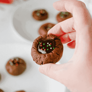 These Chocolate Thumbprint Cookies are the ultimate treat for chocolate lovers! Soft, rich chocolate cookies are filled with a smooth and creamy chocolate ganache center and topped with colorful sprinkles. This easy chocolate thumbprint cookies recipe is perfect for Christmas cookie trays, holiday baking, cookie exchanges, and homemade gifts. If you're looking for easy Christmas cookies, chocolate Christmas cookies, double chocolate cookies, or simple holiday cookie recipes, these decadent treats are a must-try! Made with cocoa powder, brown sugar, chocolate chips, and heavy cream, these homemade thumbprint cookies are loaded with rich chocolate flavor. Save this easy chocolate cookie recipe for your next holiday baking session!
