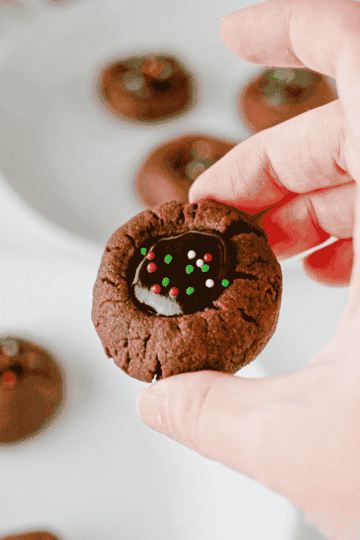 These Chocolate Thumbprint Cookies are the ultimate treat for chocolate lovers! Soft, rich chocolate cookies are filled with a smooth and creamy chocolate ganache center and topped with colorful sprinkles. This easy chocolate thumbprint cookies recipe is perfect for Christmas cookie trays, holiday baking, cookie exchanges, and homemade gifts. If you're looking for easy Christmas cookies, chocolate Christmas cookies, double chocolate cookies, or simple holiday cookie recipes, these decadent treats are a must-try! Made with cocoa powder, brown sugar, chocolate chips, and heavy cream, these homemade thumbprint cookies are loaded with rich chocolate flavor. Save this easy chocolate cookie recipe for your next holiday baking session!