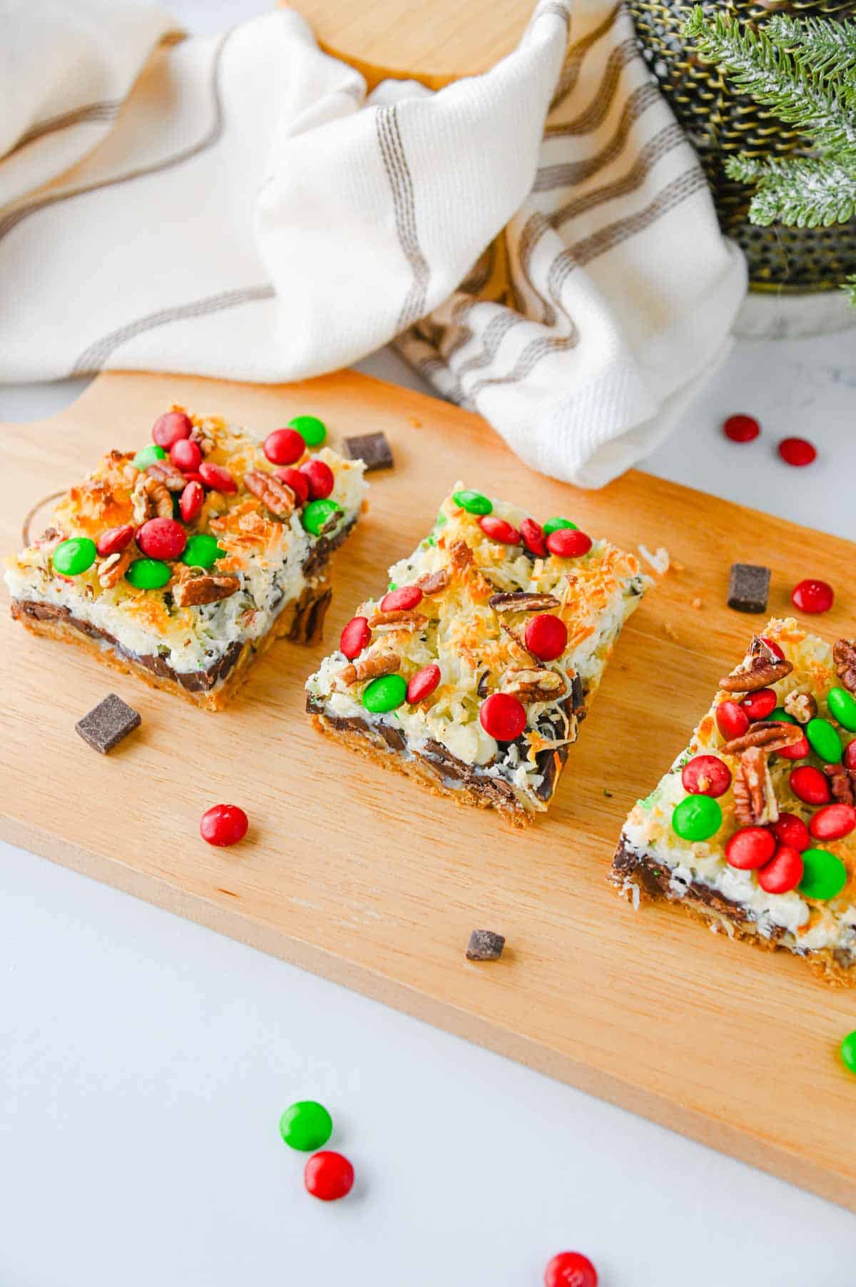 3 squares of 7 layer magic bars on a wooden board