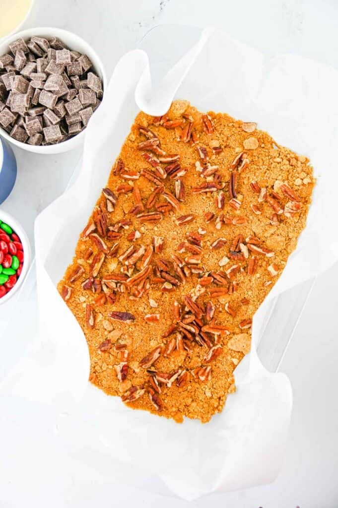 chopped pecans on top of graham cracker base in a baking dish