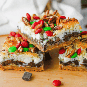These Christmas 7 Layer Bars are the ultimate easy Christmas dessert for holiday baking, cookie exchanges and festive parties! Made with a buttery graham cracker crust, crunchy pecans, semi sweet chocolate chips, white chocolate chips, sweetened coconut, gooey sweetened condensed milk and red and green M&Ms, these Christmas magic cookie bars are packed with delicious layers. This easy 7 layer bars recipe is perfect for Christmas cookie trays, holiday dessert platters, potlucks and homemade food gifts. If you love classic Hello Dolly Bars, magic bars and simple Christmas cookie bar recipes, you'll want to save this festive twist. With just 15 minutes of prep, these chewy chocolate coconut bars are an easy Christmas treat for sharing with family and friends!