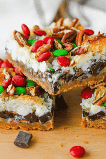 These Christmas 7 Layer Bars are the ultimate easy Christmas dessert for holiday baking, cookie exchanges and festive parties! Made with a buttery graham cracker crust, crunchy pecans, semi sweet chocolate chips, white chocolate chips, sweetened coconut, gooey sweetened condensed milk and red and green M&Ms, these Christmas magic cookie bars are packed with delicious layers. This easy 7 layer bars recipe is perfect for Christmas cookie trays, holiday dessert platters, potlucks and homemade food gifts. If you love classic Hello Dolly Bars, magic bars and simple Christmas cookie bar recipes, you'll want to save this festive twist. With just 15 minutes of prep, these chewy chocolate coconut bars are an easy Christmas treat for sharing with family and friends!