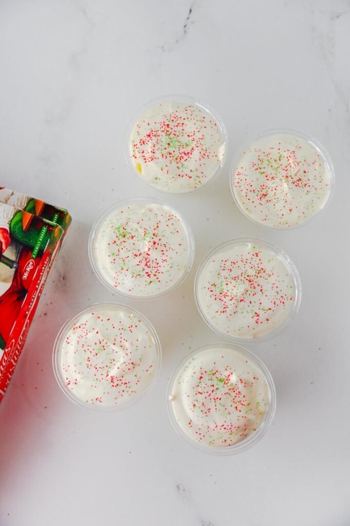 red and green sugar sprinkles on top of vanilla pudding cups